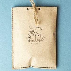 May include: A brown paper bag with a string tie and a logo that says "Four paws atelier" with a cartoon dog and cat.