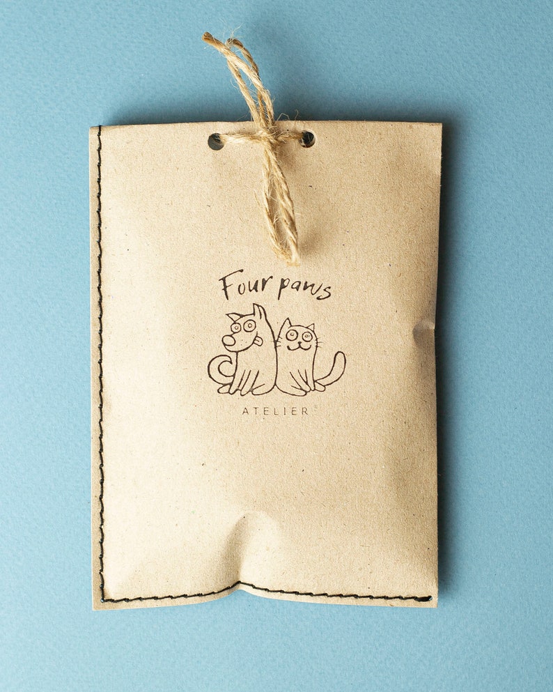 May include: A brown paper bag with a string tie and a logo that says "Four paws atelier" with a cartoon dog and cat.