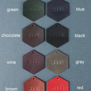 May include: Nine leather swatches in hexagon shapes, each with the word "MERE" embossed in the center. The swatches are arranged in three rows of three, with the colors green, blue, black, wine, gray, red, chocolate, and brown.
