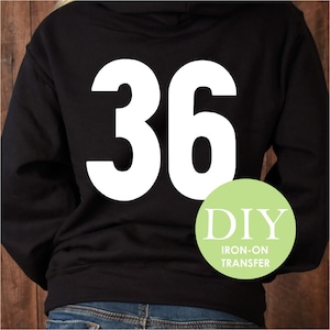 May include: Black hoodie with a white iron-on transfer of the number 36. The image also includes a green circle with the text "DIY IRON-ON TRANSFER".