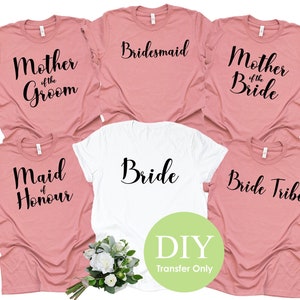 May include: Six pink and white t-shirts with black text. The shirts say "Bride", "Bridesmaid", "Mother of the Bride", "Mother of the Groom", "Maid of Honour", and "Bride Tribe".