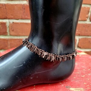 May include: A copper-toned ankle bracelet with a delicate chain and small leaf charms.