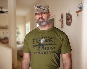 May include: A man wearing a camouflage hat and a green t-shirt with the text "This has only 2 enemies... and rust & politicians".