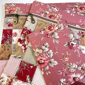 May include: A collection of three fabric pouches featuring a patchwork design with floral patterns in shades of pink, red, beige, and white. Each pouch includes a metal zipper closure with a circular pull, while the smallest item features a button.