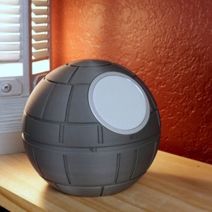 May include: A gray, spherical, decorative object with a white, circular opening. The object has a textured surface resembling a space station.
