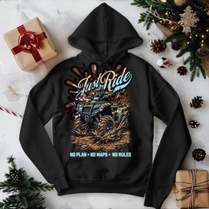 Puede incluir: Sudadera con capucha negra con un gr&aacute;fico de un ATV conduciendo por el barro. El gr&aacute;fico dice "Just Ride" y "NO PLAN - NO MAPS - NO RULES".
