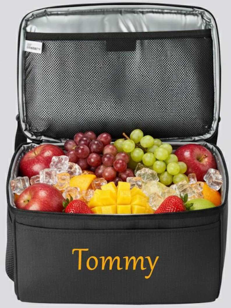 以下が含まれることがあります： 新鮮な果物（リンゴ、ブドウ、イチゴ、マンゴーなど）が詰められた黒い断熱クーラーバッグ。 クーラーには内側にメッシュポケットがあり、前面には金色の文字で「Tommy」と書かれています。