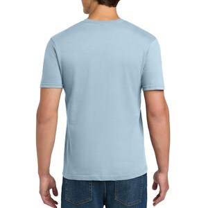 Puede incluir: Una camiseta de manga corta de color azul claro con cuello redondo, vista desde la parte posterior. La camiseta est&aacute; hecha de una tela de color s&oacute;lido y se combina con jeans de mezclilla azul oscuro. La prenda tiene un corte est&aacute;ndar.