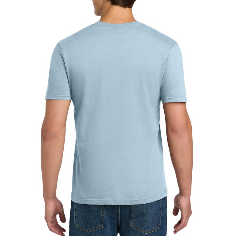 Puede incluir: Una camiseta de manga corta de color azul claro con cuello redondo, vista desde la parte posterior. La camiseta est&aacute; hecha de una tela de color s&oacute;lido y se combina con jeans de mezclilla azul oscuro. La prenda tiene un corte est&aacute;ndar.