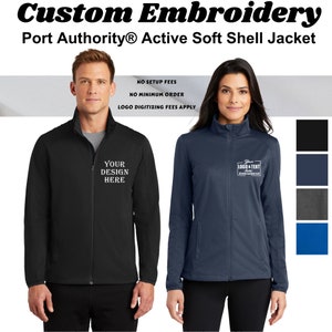 May include: A black and a navy blue soft shell jacket with a zipper closure. The jackets have a stand-up collar and are shown on two models. The text "Your Design Here" is embroidered on the black jacket and the text "Your Logo & Text Embroidered" is embroidered on the navy blue jacket.