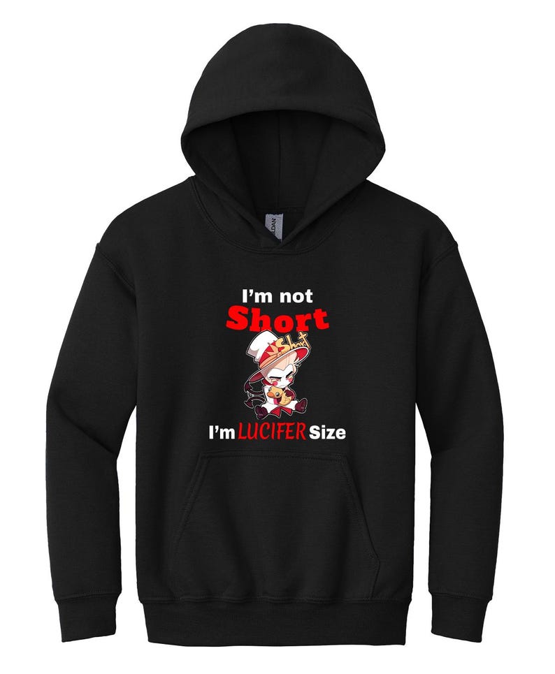 Puede incluir: Sudadera con capucha negra con un estampado gr&aacute;fico blanco de un personaje de dibujos animados con una corona y sosteniendo un coraz&oacute;n. El texto "I'm not Short I'm LUCIFER Size" est&aacute; impreso en rojo.