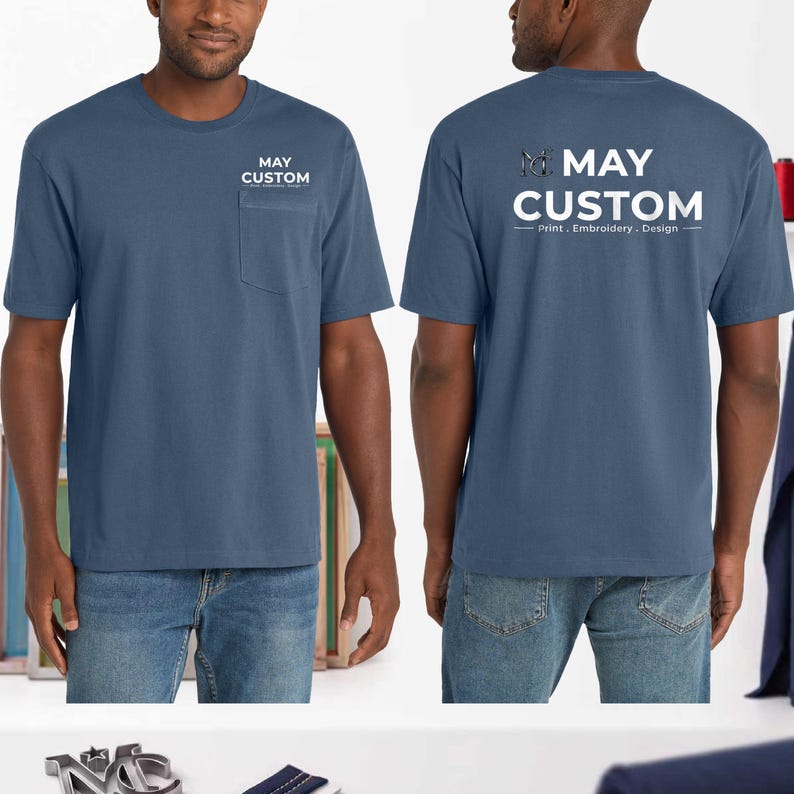 May include: A slate blue short-sleeve t-shirt with a chest pocket. The front features the white text MAY CUSTOM. The back displays a large white logo with the text MAY CUSTOM Print . Embroidery . Design and a stylized MC monogram graphic.