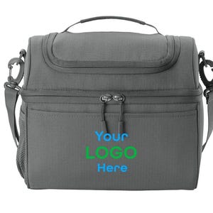 以下が含まれることがあります： グレーの断熱ランチバッグ。上部にハンドル、取り外し可能なショルダーストラップ付き。バッグにはジッパー付きのメインコンパートメントとフロントポケットがあります。「Your LOGO Here」の文字が青と緑でプリントされています。