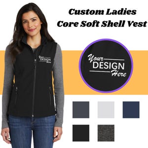 May include: Black soft shell vest with zipper closure and two pockets. The vest has a white embroidered design that says "Your Design Here". The vest is shown on a model wearing blue jeans.
