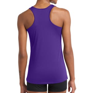 Puede incluir: Una camiseta de tirantes morada con espalda de nadador, dise&ntilde;o sin mangas, cuello redondo y dobladillo recto. La prenda est&aacute; confeccionada con un tejido liso y ligero y se lleva con pantalones cortos negros, mostrando la parte trasera de la camiseta.