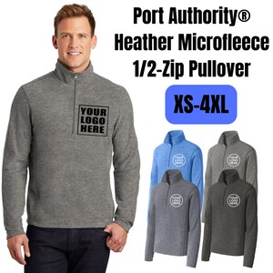 May include: A Port Authority heather microfleece 1/2-zip pullover featuring a stand-up collar and a zipper closure. The chest area displays a square box with the text YOUR LOGO HERE. Additional color variations are shown in sizes XS-4XL.