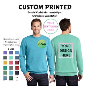 May include: A turquoise blue crewneck sweatshirt with a green and yellow logo on the front and a white rectangle with the text "YOUR DESIGN HERE" on the back. The sweatshirt is garment-dyed and has a beach wash finish. The text "YOUR TEXT/LOGO HERE" is also visible on the image.