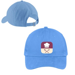 May include: A light blue baseball cap with a white chef hat and crossed spoon and fork graphic on the front. The graphic is inside a square with a burgundy background and a beige border.