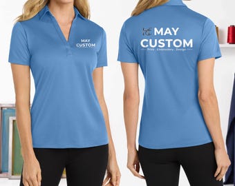 May include: A light blue polo shirt with a V-neck collar and short sleeves. The front features the white text MAY CUSTOM. The back displays the white text MAY CUSTOM with the subtext Print, Embroidery, Design and a logo featuring the letters MC.