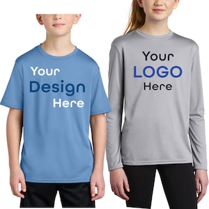 May include: Two children wearing athletic shirts. One shirt is light blue with the text "Your Design Here" in white and dark blue. The other shirt is gray with the text "Your LOGO Here" in dark blue and black. Both shirts are short-sleeved.