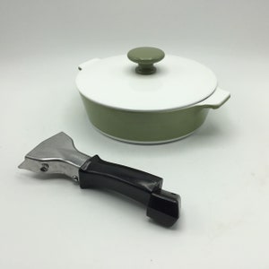 May include: A green ceramic pot with a white lid and a knob on top. The pot has a matching green handle on the side. A silver and black handle is also included.