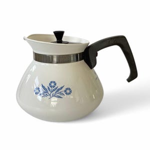 May include: White ceramic coffee pot with a black handle and lid. The pot has a blue and white floral design.