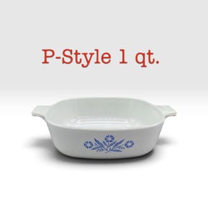May include: A white square baking dish with integrated side handles and a blue floral pattern on the front. The text P-Style 1 qt. is printed in red above the dish. The vessel features a smooth finish and a wide, open top design.