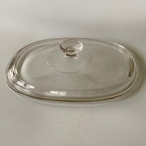 May include: Clear glass lid for a casserole dish with a round knob on top.