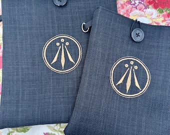 Broderad bokomslag med Druid Awen-symbol