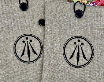 Broderad bokomslag med Druid Awen-symbol