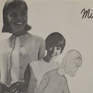 May include: Three women wearing sweaters. The woman on the left is wearing a light gray cardigan over a white shirt. The woman in the middle is wearing a white sweater. The woman on the right is wearing a gray sweater. The image is in black and white.