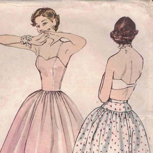 以下が含まれることがあります： ヴィンテージ Simplicity パターン 3739。3 つのドレスのイラストが特徴です。メインのドレスはピンク色で、ストラップレスのデザインで、フレアスカートが付いています。パターンの詳細は各ピースに印刷されています。サイズ 16、バスト 86 cm。