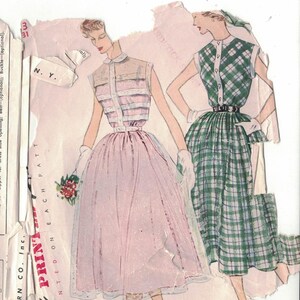 Puede incluir: Patrón Simplicity vintage con ilustraciones de vestidos. Un vestido es rosa claro con falda amplia, el otro es de cuadros verdes. El patrón incluye requisitos de tela y medidas corporales en cm.