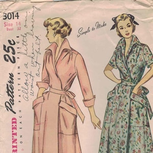 May include: Vintage Simplicity pattern featuring two dress designs. One is a long, light pink wrap dress with large pockets and a belt. The other is a floral print dress with a collared top and a flared skirt. The pattern includes the text "Simple to Make".