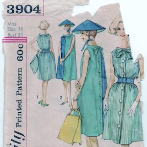 Puede incluir: Un patrón de costura vintage para un vestido con un detalle de lazo. El patrón es para una talla 14 y tiene una medida de pecho de 86 cm. El patrón está impreso en un fondo rosa claro con un borde rosa oscuro. El patrón se titula "Simplicity Printed Pattern 60c" y tiene el número "3904" impreso en la parte superior.