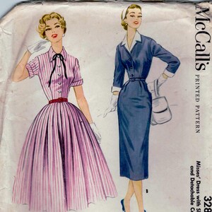 May include: Vintage McCall's printed pattern featuring illustrations of two dresses. One dress is pink and white striped with a full skirt, the other is a blue dress with a slim skirt. The pattern includes detachable collar and cuffs.