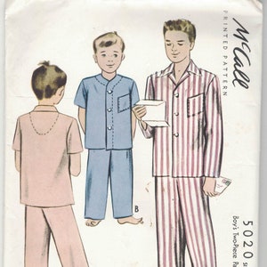 Peut inclure: Un patron de couture vintage pour pyjama de garçon. Le patron montre deux garçons portant des pyjamas, l'un en bleu et l'autre en rose et blanc à rayures. Le numéro du patron est 5020, taille 6, et est pour un pyjama deux pièces.