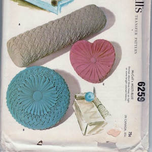 May include: A vintage McCall's transfer pattern for three smocked pillows, a 30-inch bolster, and a 13-inch heart. The pattern is called "McCall's Multi-Blue" and costs 75 cents. The pattern includes instructions in French and Spanish.
