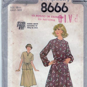 May include: Simplicity sewing pattern number 8666 for a dress. The pattern includes instructions for a "fuss-free fit" and is for a half-size 18 1/2. The pattern cover shows two models wearing the dress. One model is wearing a brown dress with a floral print and the other is wearing a solid brown dress.