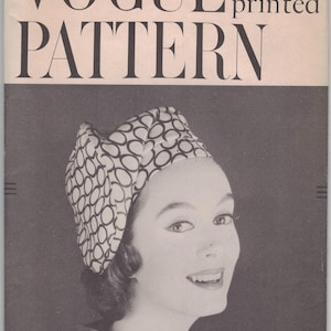 Puede incluir: Portada de patrón Vogue vintage con una mujer que lleva un tocado estampado. La portada incluye el texto "VOGUE printed PATTERN" y "AN ORIGINAL BY John Frederics". Talla de cabeza 22.