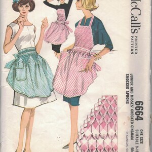 May include: Vintage McCall's sewing pattern for junior and misses' checked gingham smocked aprons. The pattern features illustrations of aprons in pink and blue gingham, with a retro design. The pattern number is 6664.