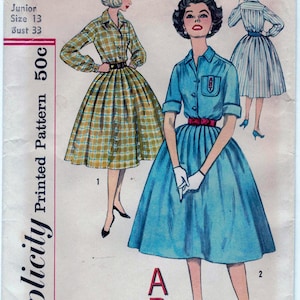 Puede incluir: Patrón de costura Simplicity número 2627 para un vestido junior talla 13 con una talla de pecho de 84 cm. El patrón incluye dos estilos de vestidos diferentes, uno con estampado a cuadros y el otro con tela azul sólida. Ambos vestidos tienen un cuello de camisa abotonado y una falda completa.