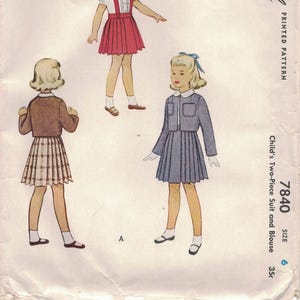 May include: A vintage McCall's sewing pattern for a child's two-piece suit and blouse. The pattern shows illustrations of three outfits: a red skirt and white blouse, a grey suit, and a skirt and jacket. The pattern is size 6.