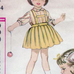 May include: A vintage sewing pattern illustration of a young girl wearing a yellow and white striped dress with a matching blouse. The girl is holding a red ball on a string. The pattern number is 1064.