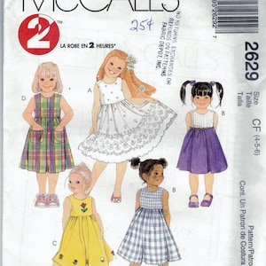 May include: Sewing pattern for four girls' dresses. The pattern is for sizes 4-5-6. The dresses are in different styles and colors, including plaid, gingham, and floral.