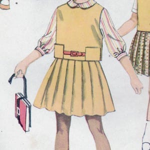 May include: A vintage sewing pattern for a girl's dress with a yellow skirt and a white blouse with a striped collar. The pattern includes a belt and a small purse.