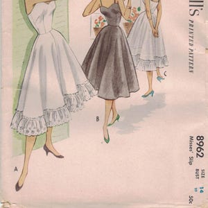 May include: Vintage McCall's pattern featuring illustrations of three dresses. The dresses are in white and charcoal gray, with a flared skirt and spaghetti straps. The pattern number is 8962, size 14, bust 32 inches.