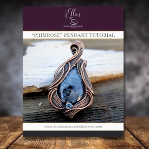 以下が含まれることがあります： 銅色のワイヤーラップペンダント。涙型の青灰色の石が特徴です。木製の表面に展示されており、背景には「Primrose Pendant Tutorial」とウェブサイトアドレスが記載されたチュートリアルカバーがあります。