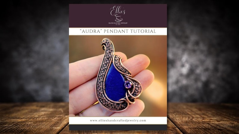 May include: A tutorial for making a wire wrapped pendant called "Audra". The pendant features a blue gemstone set in a copper wire frame. The tutorial is available on the website ellieshandcraftedjewelry.com.