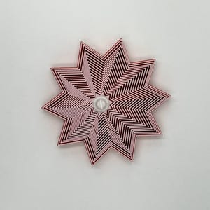 May include: A set of red metal cookie cutters in the shape of a star. The cutters are nested inside each other, creating a layered effect.
